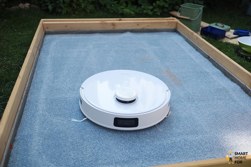 Ecovacs Deebot T10 reinigt im Test Sand auf einem hohen Teppich.